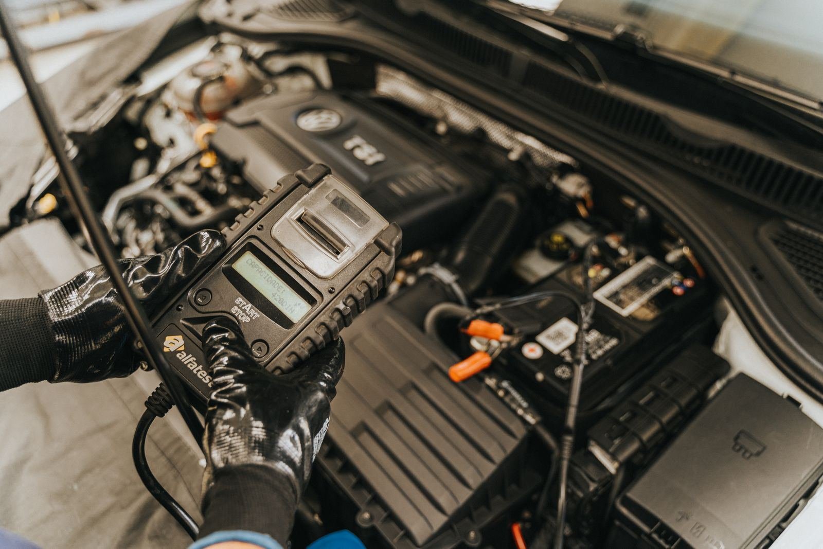 Photo – auto electrician testing a battery in a car engine bay